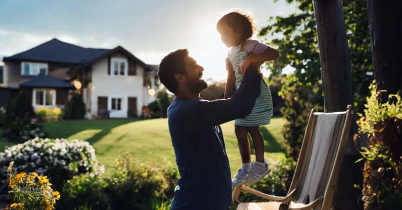 Father holding up daughter in backyard