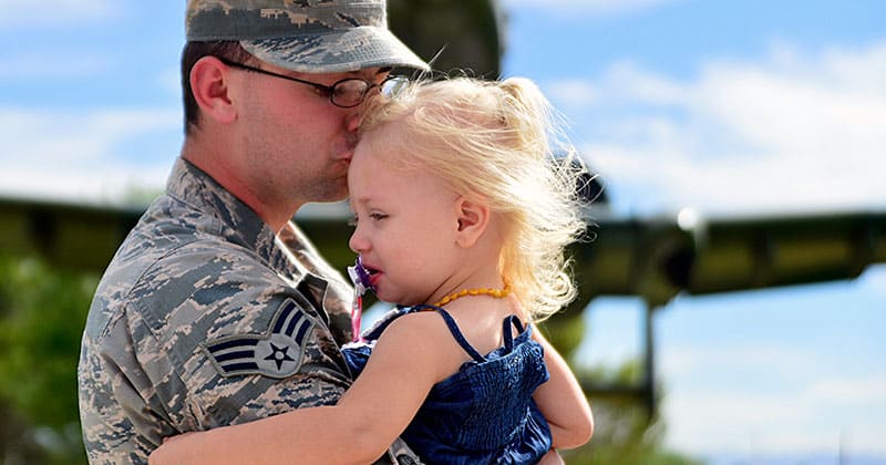 Man in uniform kissing daughter on forehead